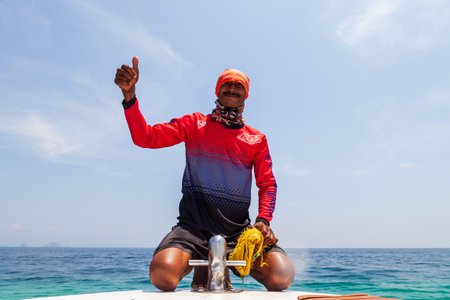 Thailand, Phuket - 01.04.23: A sailor on a speedboat manages the equipment of a boat for transporting tourists on excursions around the islands. Hard work on a ship.のeditorial素材