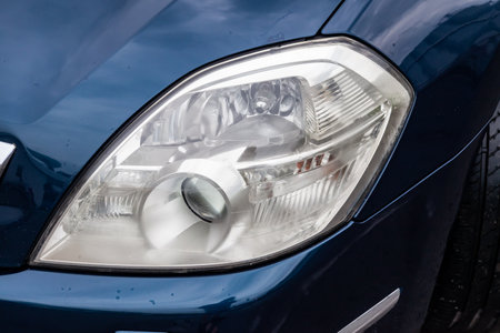 Front headlight view of car in blue color after cleaning and detailing with washer before sale. Big...
