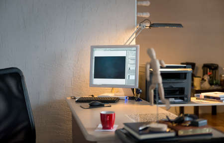 Desk with a computer with a red cup, lamp surrounding space