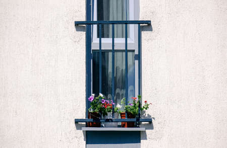 French balcony with flowers on the background of the white house