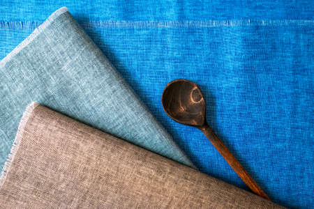 Aged wooden spoon on kitchen linen napkinsの写真素材