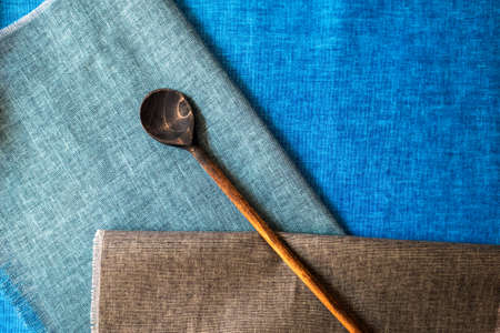 Aged wooden spoon on kitchen linen napkins