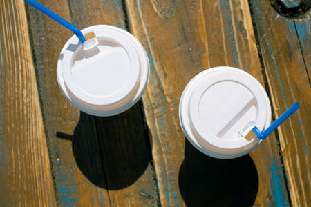 Two white coffee paper cups on the wooden background with tubesの写真素材