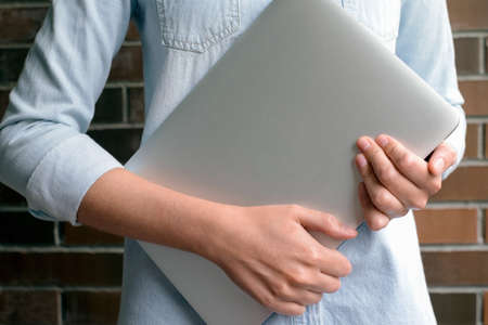 Girl hands holds an aluminum laptop in the daytimeの写真素材