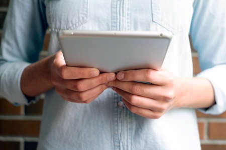 Girl holds an aluminum tablet computer in the daytimeの写真素材