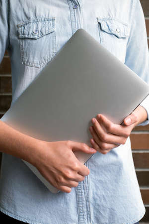 Girl hands holds an aluminum laptop in the daytimeの写真素材