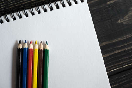 Colored pencils on white sketchbooks on a wooden background