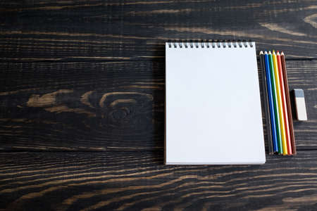 Colored pencils on white sketchbooks on a wooden backgroundの写真素材