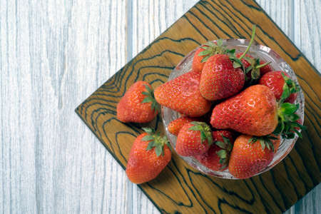 Strawberries in a bowl on a white wooden backgroundの写真素材
