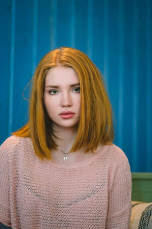 Portrait of red-haired girl on the background of blue wall. Redhead.の写真素材