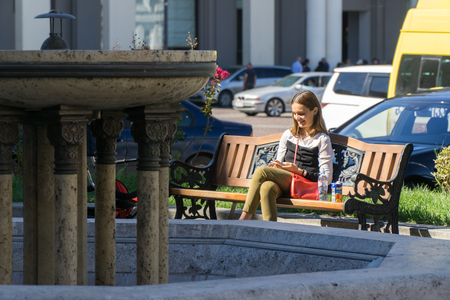 Tbilisi, Georgia-SEP 25, 2016: the girl with the phone sits on the bench at liberty squareのeditorial素材