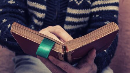 Man holding an old book in his hands, with a ribbon between the pagesの写真素材
