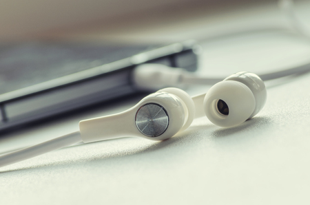 White headphones and smartphone on a light backgroundの写真素材