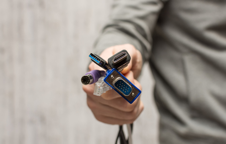 Hand holding out a bunch of computer cables with different connectorsの写真素材