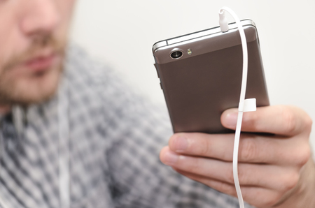 Man listens to music on headphones, from his phoneの写真素材