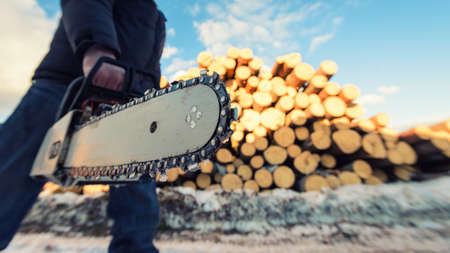 man with chainsaw during logging working on a sawmillの写真素材