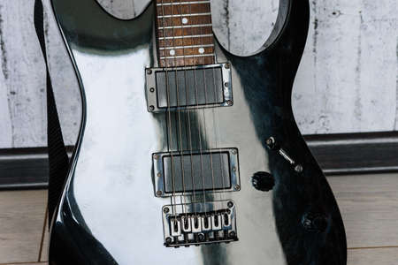 black electric guitar with metal strings close up on a blurred background