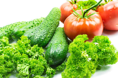 Fresh tomatoes and cucumbers, vegetables and parsley on a white backgroundの写真素材