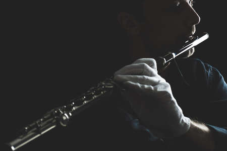flutist in a black shirt, against a dark background .. male executor on a wooden wind instrumentの写真素材