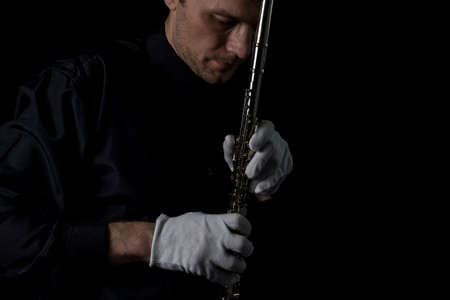 flutist in a black shirt, against a dark background .. male executor on a wooden wind instrumentの写真素材