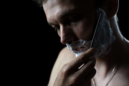 man with a dangerous razor for shaving on a dark background