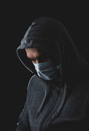 man in a medical mask on a black background, protection against coronavirus, disease prevention