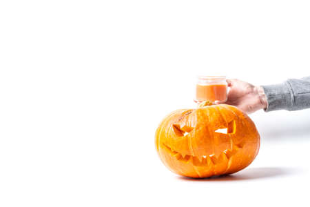 a man lays a burning candle in the jack's lantern from a pumpkin prepared for Halloween, a face cut with a knifeの写真素材