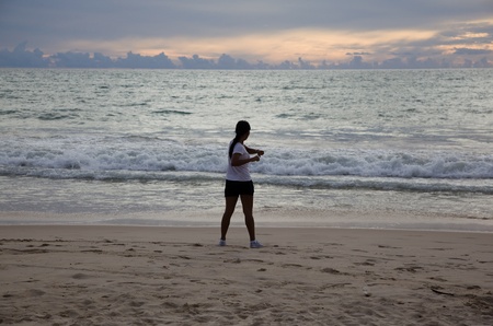 Thai girl doing gymnastics on the beach at sunset  Phuketの写真素材