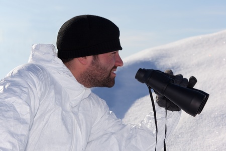Commandos in white camouflage looking through binoculars in the mountains on the white snowの写真素材