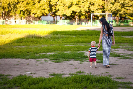 Baby boy walking in the park with moms supportの写真素材