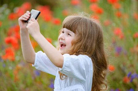 Child is taking photo with mobile phone camera outdoor in natureの写真素材