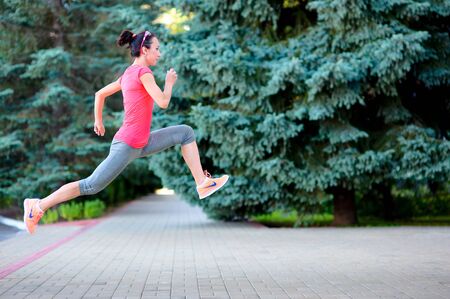 Sporty woman running and jumping in street. Female urban athlete training outdoor.