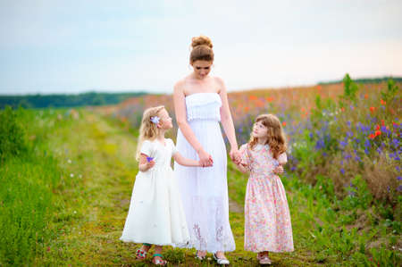 Happy woman with kids walking near the poppy fieldの写真素材