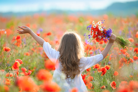 kid girl move thru blooming field with red wild flowersの写真素材