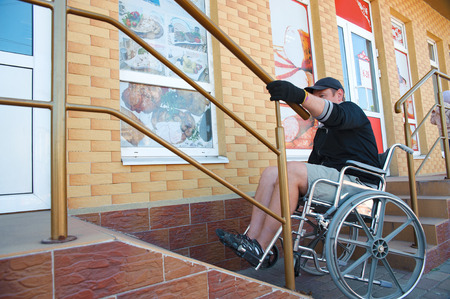 A disabled man on Wheelchair trying to climb ramp entrance. Handicapped male make their way into the...