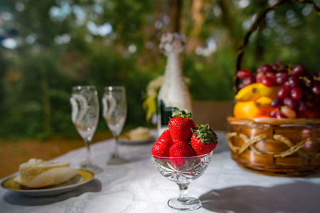 strawberries in a bowl on a table with other fruits and drinks. Festive picnic outdoors.の写真素材
