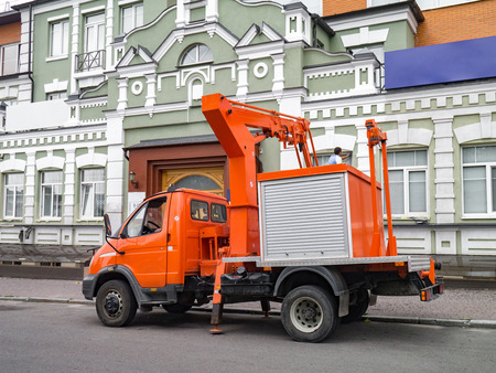 Modern, small, bright orange aerial access platform next to a historic building