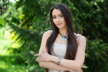Young woman shows jewelry isolated on spring nature backgroundの写真素材