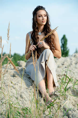 Pretty woman in casual clothes sit on the sandの写真素材