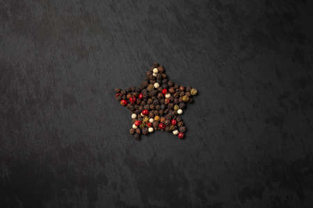 Peppercorn pepper on a black background, laid out in the shape of a star. Red, white, black peppersの写真素材