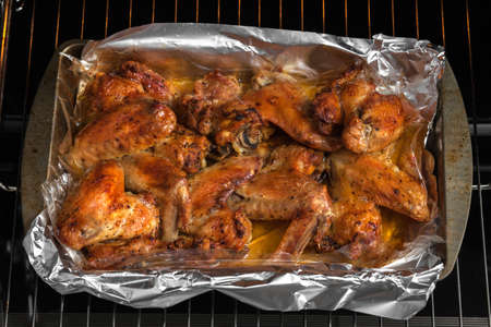 Oven baked chicken wings in the home kitchen. With a golden crispy crust. Close-up