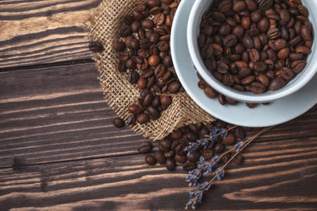 Coffee cup with coffee beans and sprigs of lavender on a wooden tabletopの写真素材
