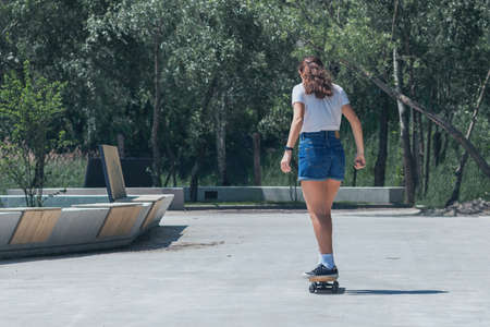 Teen girl skateboarding in the park. In sunny weather, on a hot summer dayの写真素材