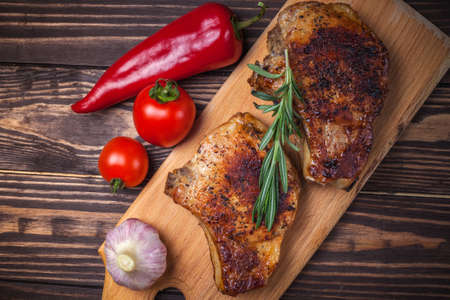 Grilled pork steaks and vegetables on a rustic wooden table. Grilled meat on the bone with spicesの写真素材