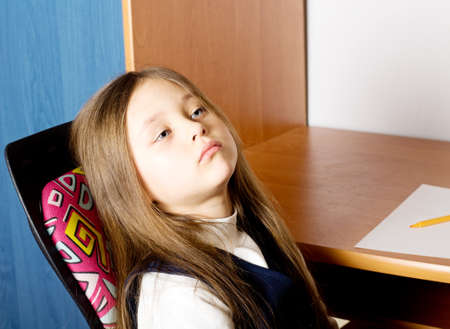 little tired pretty girl with long hair sitting in a chairの写真素材