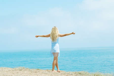 girl standing on the beach arms outstretched to the sidesの写真素材
