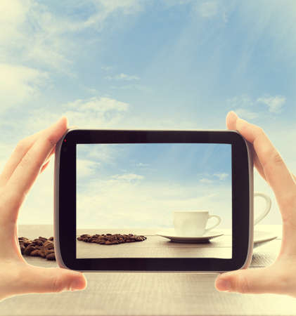 hands with electronic tablet take pictures a cup of coffeeの写真素材