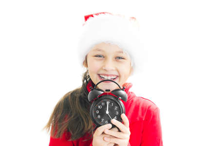 little girl in Santa Claus hat holding alarm clock showing twelve o'clockの写真素材