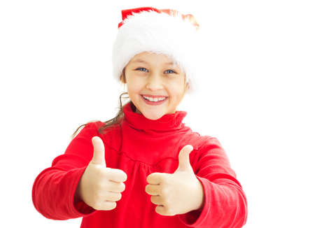little girl in a Santa Claus hat shows two thumbs up on white isolated background