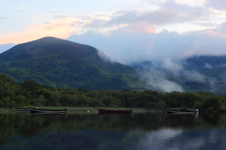 Boats on the lake at the foot of the mountain, sunsetの写真素材